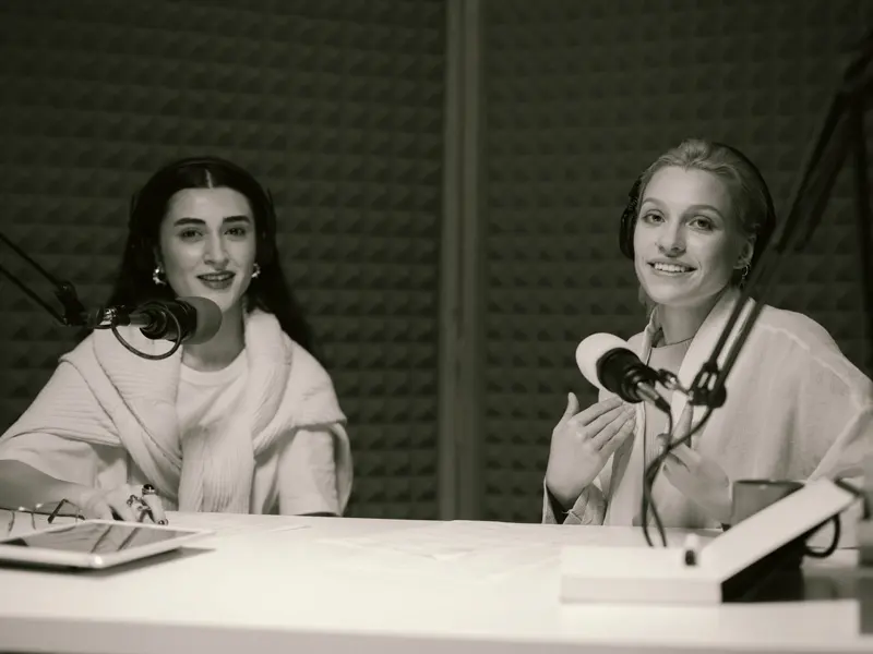 Two podcast hosts recording an episode with headphones and microphones